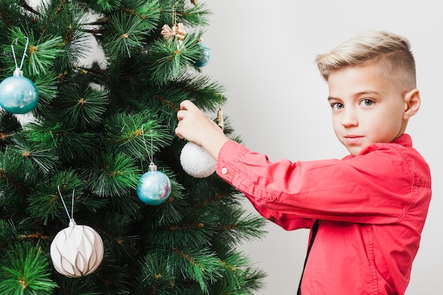 Niño joven decorando árbol de navidad