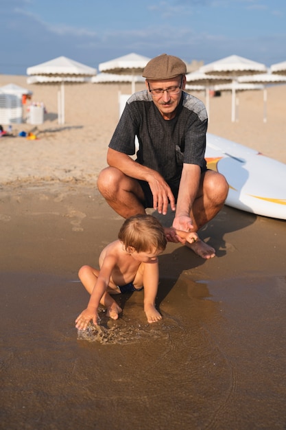 Niño jugando en el agua con el abuelo al lado