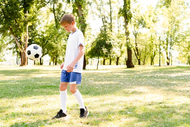 Niño jugando al fútbol con espacio de copia