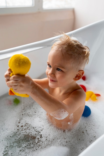 Niño jugando en la bañera con juguetes
