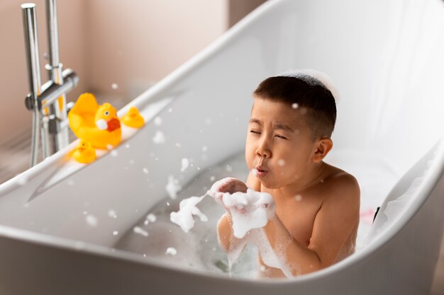 Niño jugando en la bañera con juguetes