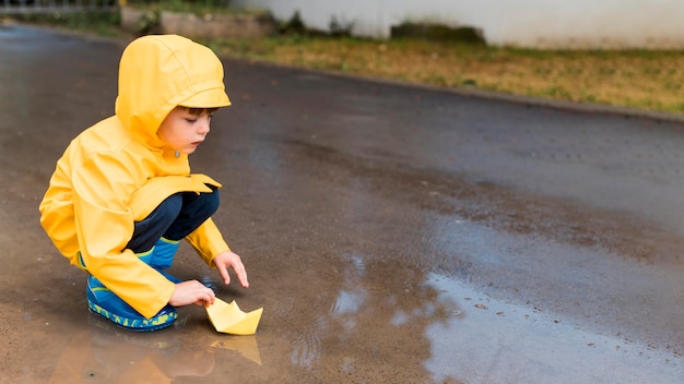 Foto gratuita niño jugando con un bote de papel con espacio de copia