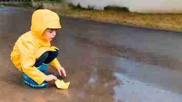 Foto gratuita niño jugando con un bote de papel con espacio de copia