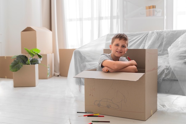 Niño jugando en una caja antes de mudarse con su familia