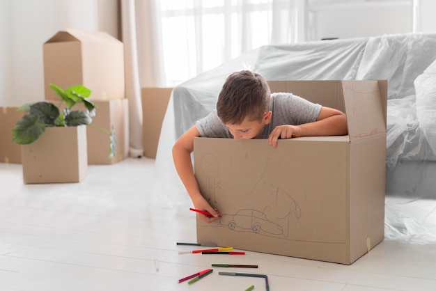 Niño jugando en una caja antes de mudarse con su familia