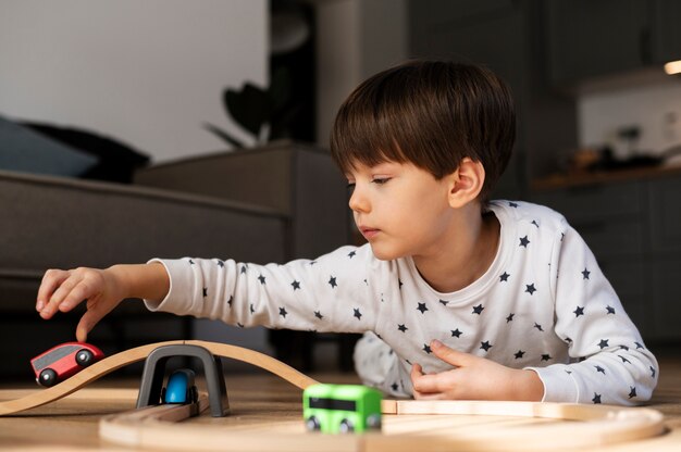 Niño jugando con carro de madera plano medio