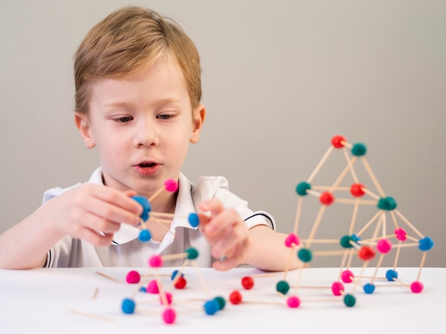 Niño jugando con colorido juego de átomos en casa