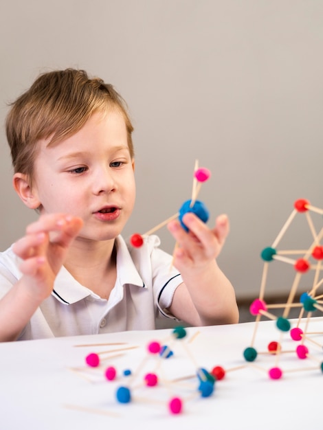 Niño jugando con colorido juego de átomos en el interior