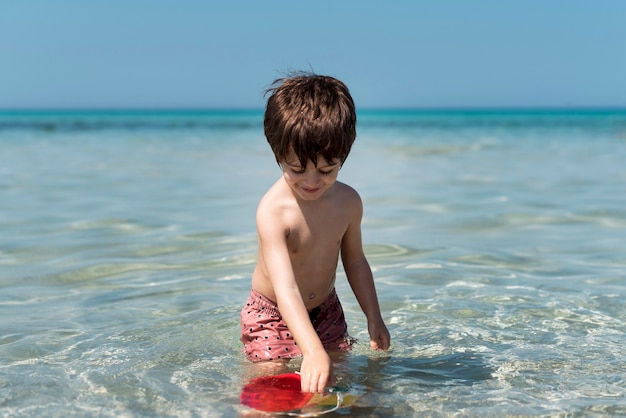 Niño jugando con el cubo en el agua