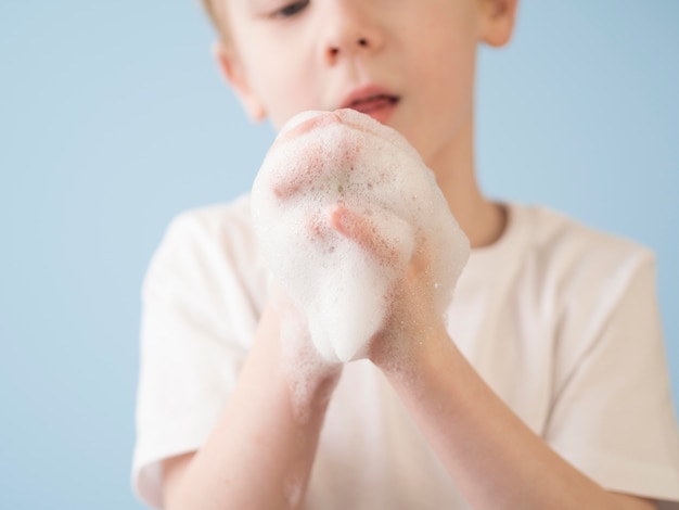 Niño jugando con espuma mientras se lava