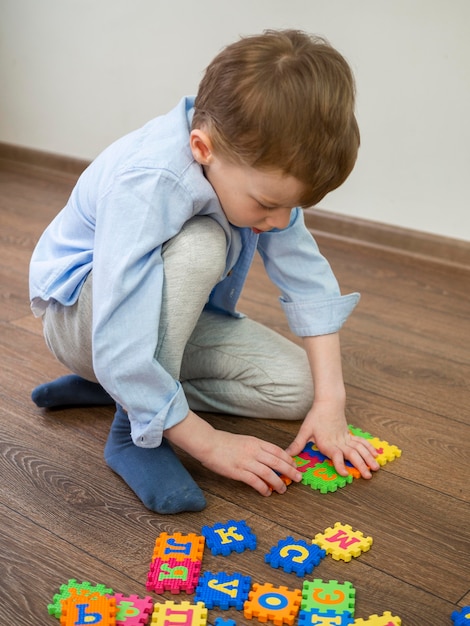 Foto gratuita niño jugando con el juego del alfabeto en casa