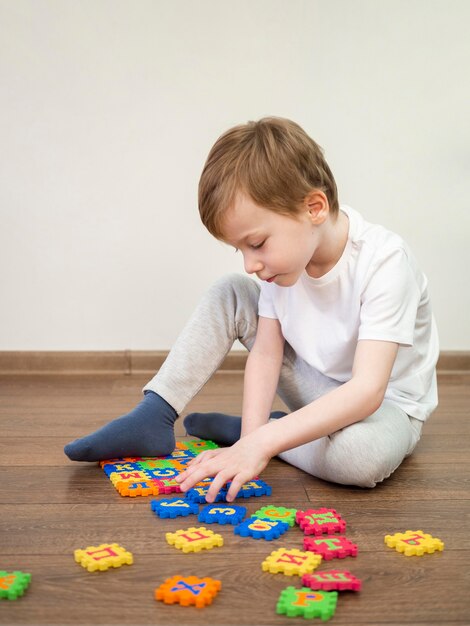 Niño jugando con el juego del alfabeto en interiores