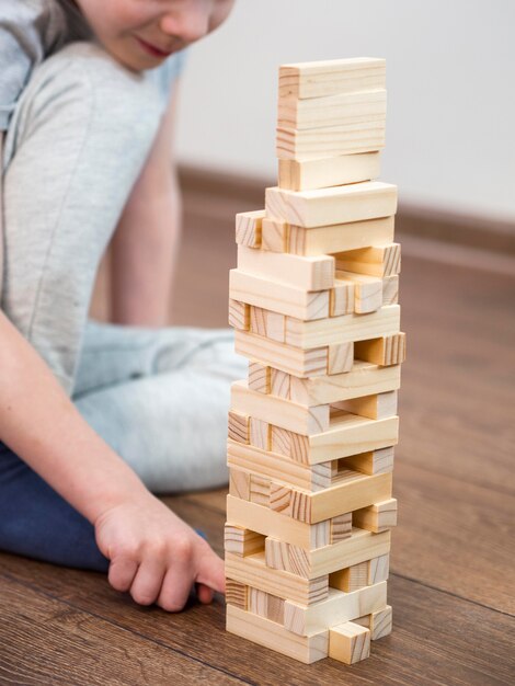 Niño jugando con juego de torre de madera en el piso