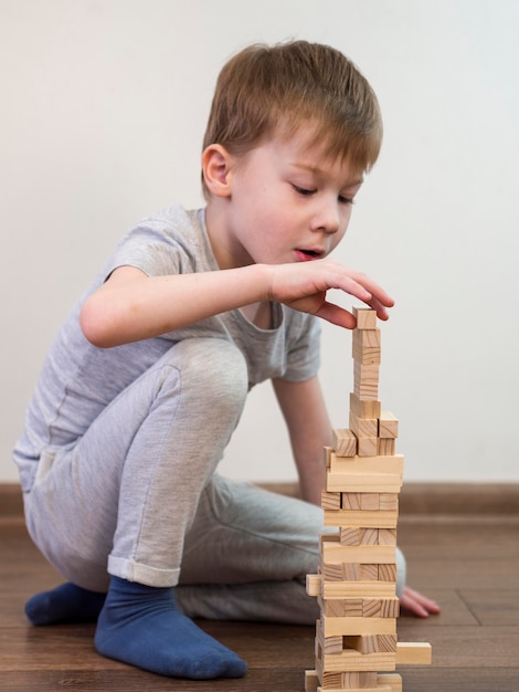 Niño jugando con juego de torre de madera en el piso