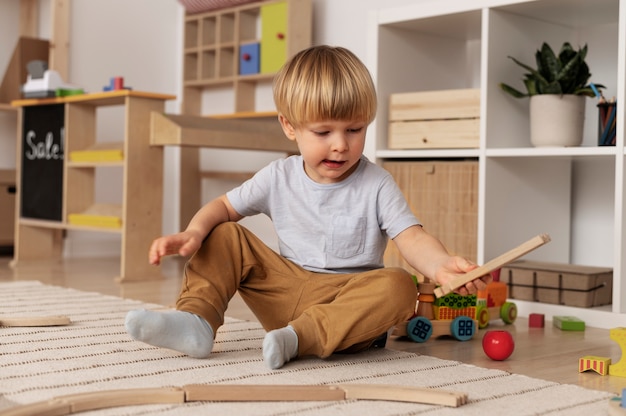 Niño jugando con juguetes de madera tiro completo