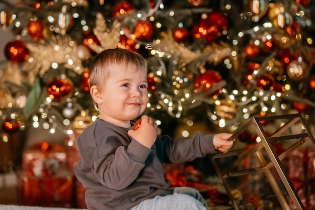 Niño jugando junto al árbol de navidad
