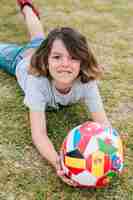 Foto gratuita niño jugando con la pelota en el césped