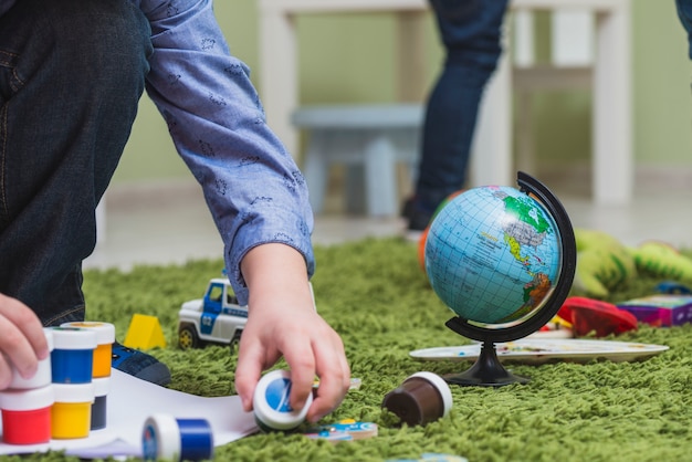 Foto gratuita niño jugando pinturas en el piso