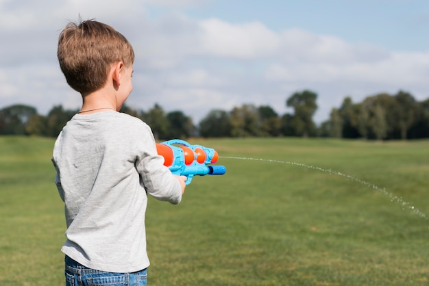 Niño jugando con una pistola de agua sobre el hombro