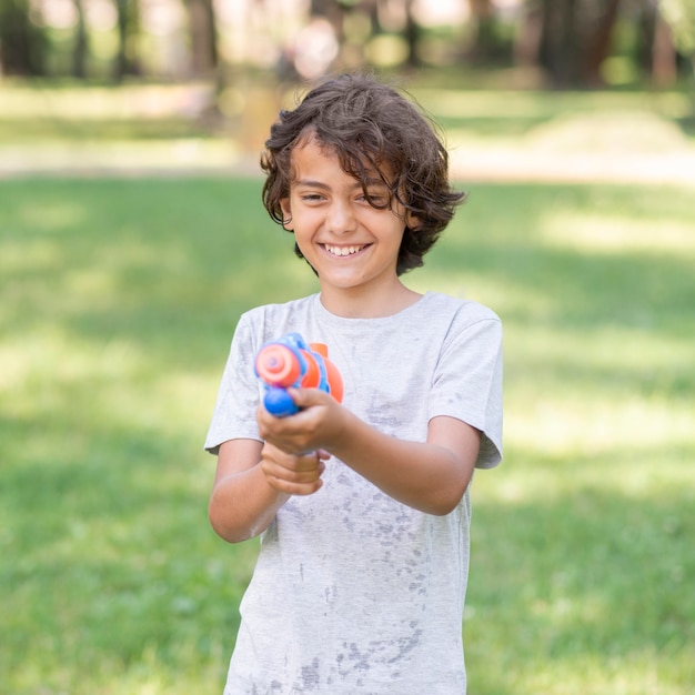 Foto gratuita niño jugando con pistola de agua