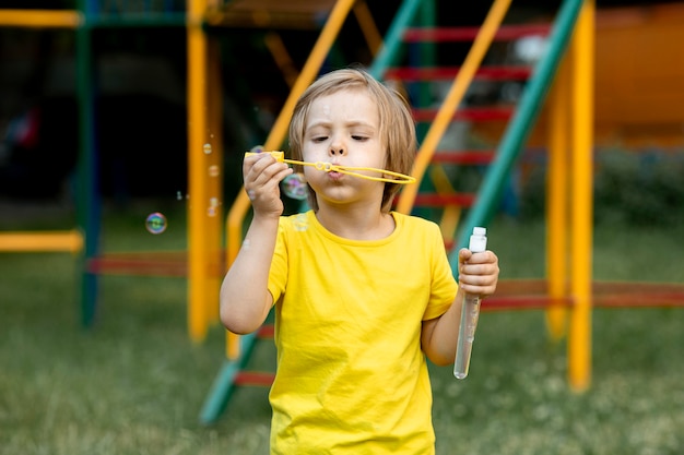 Niño jugando con pompas de jabón al aire libre