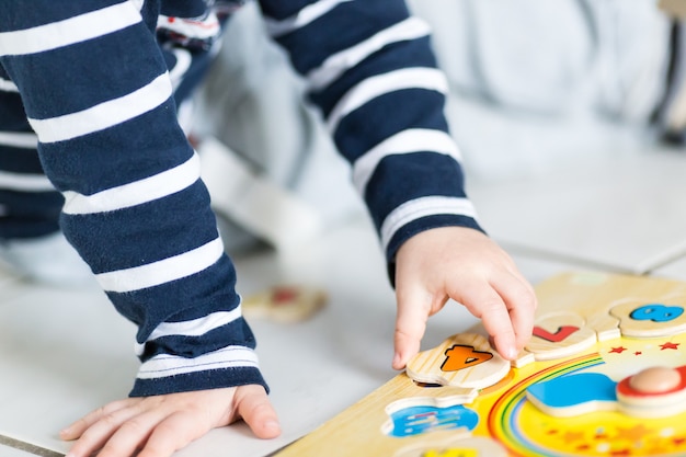 Foto gratuita un niño está jugando con un rompecabezas de reloj de madera