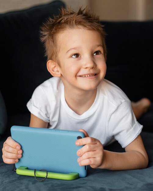 Niño jugando en el sofá en el teléfono inteligente