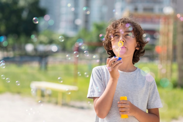 Niño jugando con soplador de burbujas al aire libre