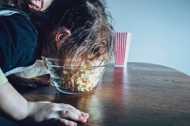 Niño juguetón comiendo palomitas de maíz de tazón