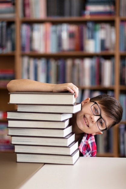 Niño juguetón escondido detrás de la pila de libros