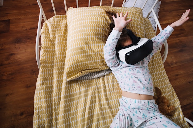 Niño juguetón en gafas VR en la cama