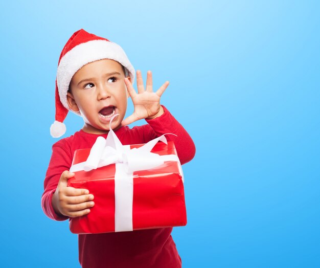 Niño juguetón mostrando su regalo con fondo azul