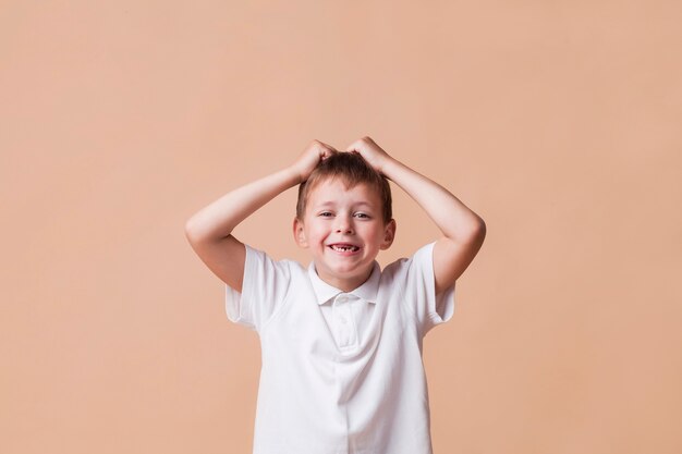 Niño juguetón con su hermosa sonrisa mirando a la cámara sobre fondo liso