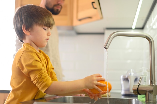 Foto gratuita niño lavando un limón en el fregadero