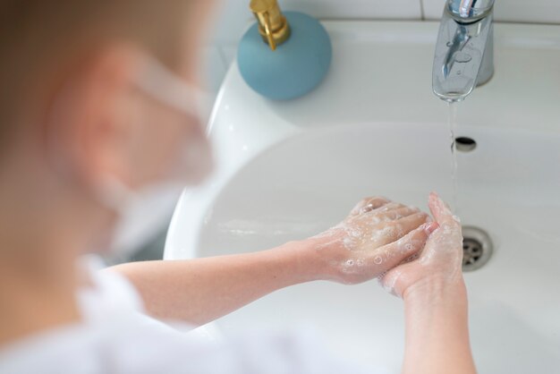 Niño lavando sus manos sobre la vista del hombro