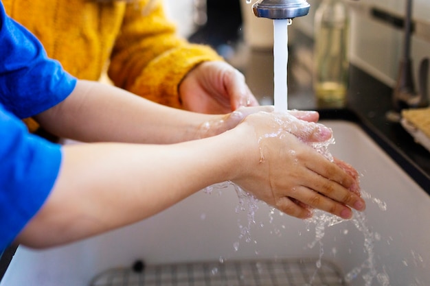 Niño lavándose las manos en el fregadero