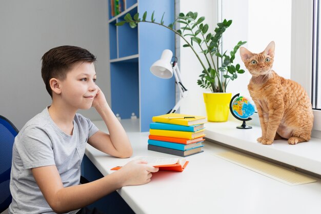 Niño leyendo y mirando gato