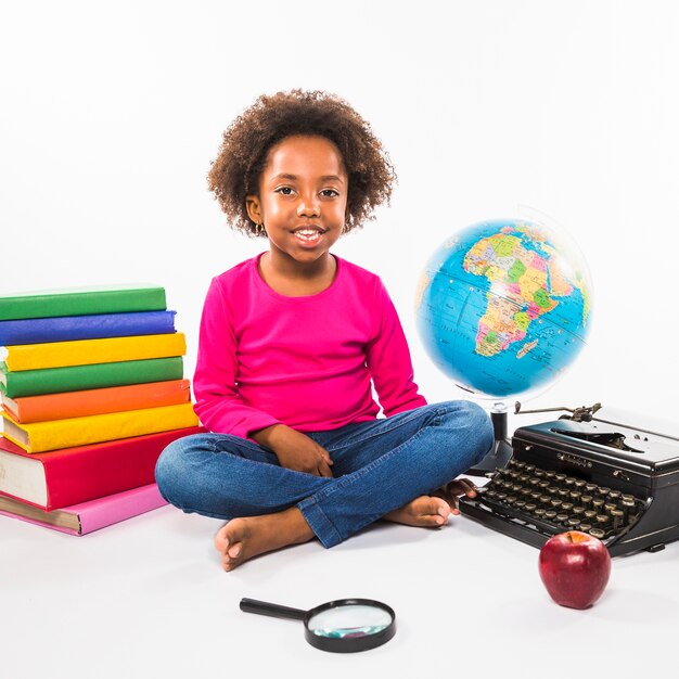 Niño con libros globo y máquina de escribir en estudio