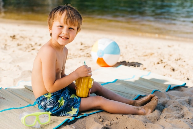 Niño lindo alegre que sonríe en la costa