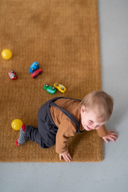 Foto gratuita niño lindo de alto ángulo con juguetes en el piso