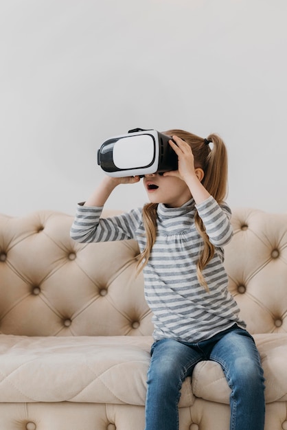 Niño lindo con casco de realidad virtual y sentado en el sofá