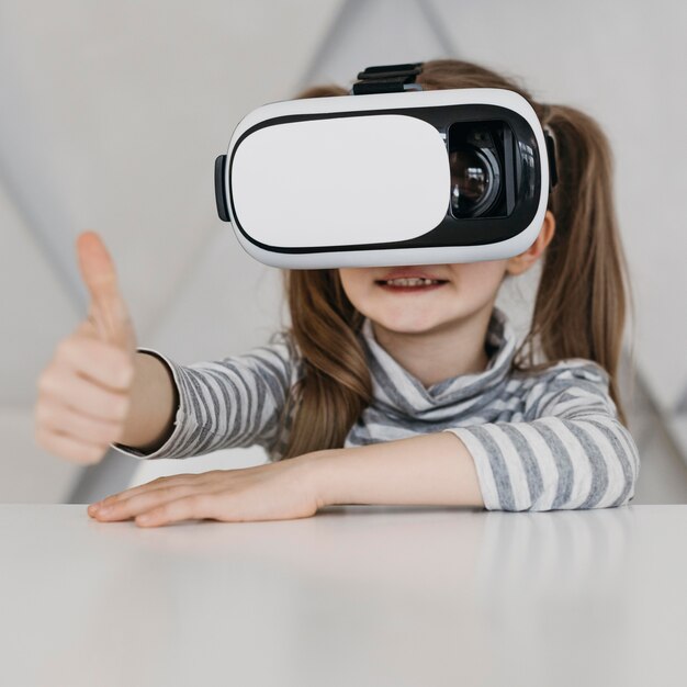 Niño lindo con casco de realidad virtual Thumbs up