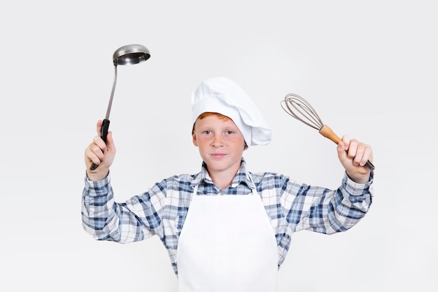 Niño lindo con herramientas de cocina