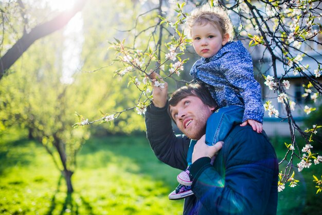 Niño lindo en los hombros de su padre en el parque