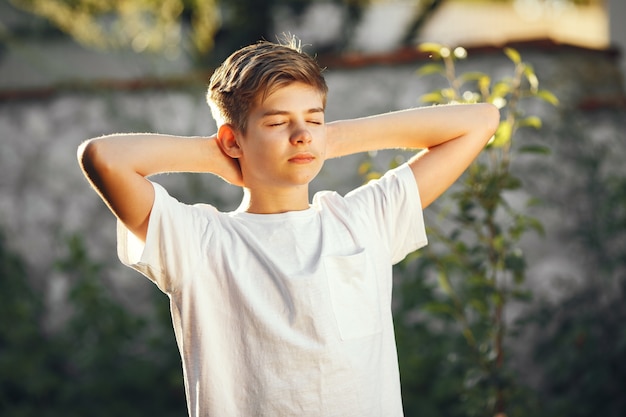 Niño lindo en un jardín. Niño con camiseta blanca.