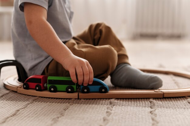 Niño lindo jugando con vista lateral del tren de madera