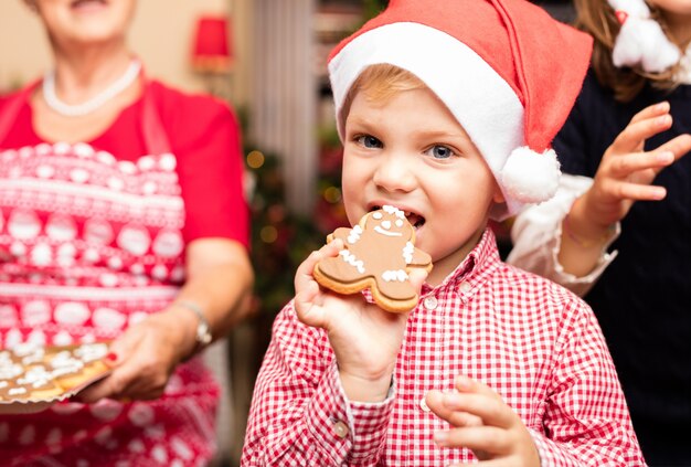 Niño lindo mordiendo una galleta de navidad