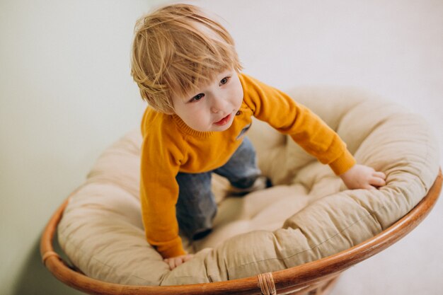 Niño lindo sentado en una silla