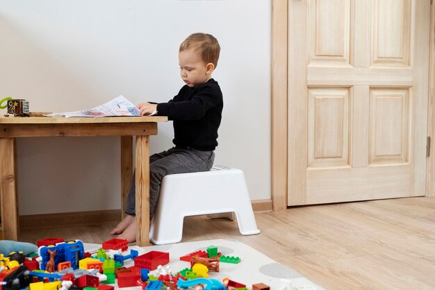 Niño lindo de tiro completo dibujando en la mesa