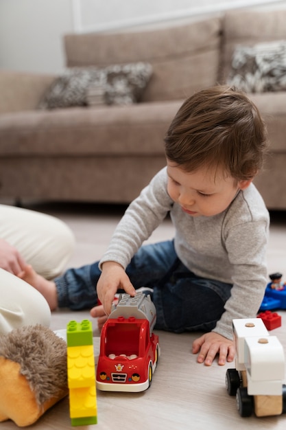 Foto gratuita niño lindo de tiro completo jugando con auto